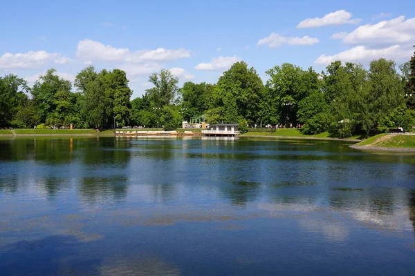 Ostankino Park'ta gölet ve rekreasyon alanı. İnsanlar gezinti boyunca yürüyor.