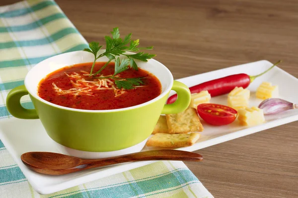 Tomato soup in a green cup on a checkered tablecloth