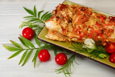 Tünek terbiye edildi. Beyaz bir masada yeşil tabakta sebzeli fırında balık.