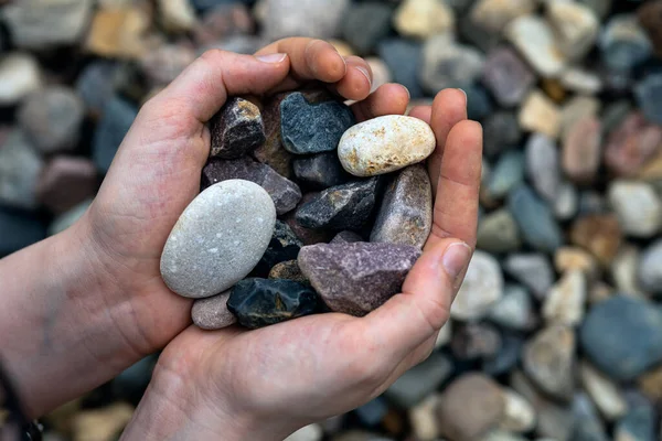 A handful of stones in hands against a background of stone pebbles for summer cottages and gardening