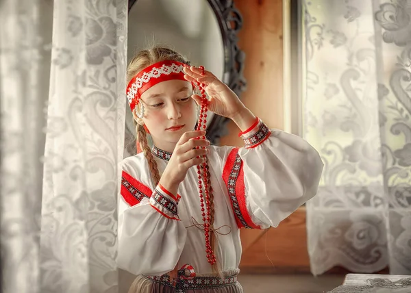 美しいドレスのかわいい女の子は ローワンベリーで作られたビーズを見ています 美しい少女が何かを考えた ロシアの伝統 — ストック写真