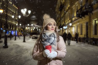 Eldivenli genç bir bayan ve bir kış gecesinde ışıkların altında bir şapka. St. Petersburg 'da güzel bir kızın kış portresi. Bir fincan kahveyle güzel bir Noel gecesi.