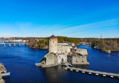Beautiful aerial view of Olavinlinna, Olofsborg ancient fortress, the 15th-century medieval three - tower castle located in Savonlinna city on a sunny summer day, Finland. Shooting from a quadcopter. clipart