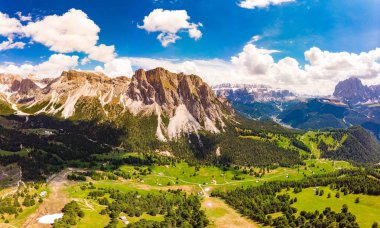 Güneşli yaz gününde drone'dan Col Raiser platosuna havadan üstten manzara. Çimenli yamaç köyü St Cristina di Val Gardena, Bolzano, Seceda İtalya yeşil vadi ile engebeli Sella Dağı Manzarası.