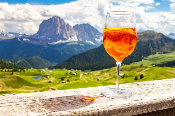 Renkli İtalyan çayırları ve Dolomites Alpleri dağlarının arka planında geleneksel İtalyan alkollü içkisi Aperol Spritz'in manzarası. köy St. Cristina di Val Gardena Bolzano Seceda, İtalya.