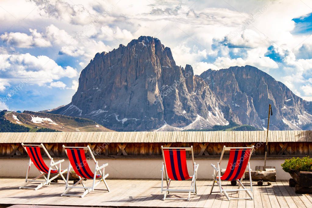 beautiful view to place of rest with sunbeds near funicular Col Raiser, captured with one of the dolomites famous mountains, the Sassolungo or Longkofel, in the background, on sunny summer clear day.