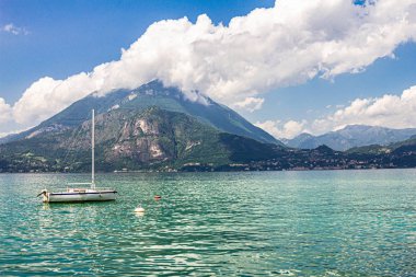 Como Gölü'ndeki Varenna köyünde limana demirlemiş yelkenlinin manzarası. Arka plan alpler dağlar, ağaçlar ve su üzerinde Manzara manzara. Lecco Milano Eyaleti. İtalyan bölgesi Lombardiya, İtalya Avrupa
