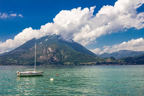 Vista alla barca a vela ancorata nel porto del paese di Varenna sul Lago di Como. Paesaggio panoramico su sfondo alpi montagne, alberi e acqua. Milano Provincia di Lecco. Regione italiana Lombardia, Italia Europa — Foto Stock