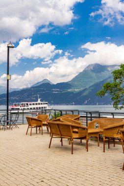 Yüksek dağlara ve Como sahil gölüne bakan teras kafenin güzel manzarası. Boş hasır restoran sandalyelervarenna antik kentinde şık bir restoranda misafirler bekliyor.