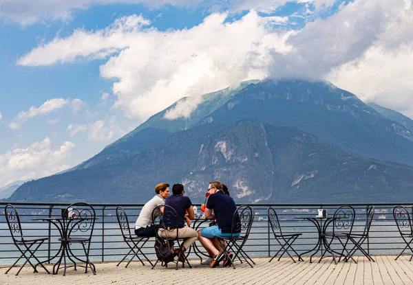 Varenna italya 26.07.2019: Avrupa halkı yaz güneşli gününde yüksek dağların ve sahil gölü Como'nun güzel manzarasına sahip teras kafede kahvaltı ediyor. Antik İtalyan şehrinde şık restoran.