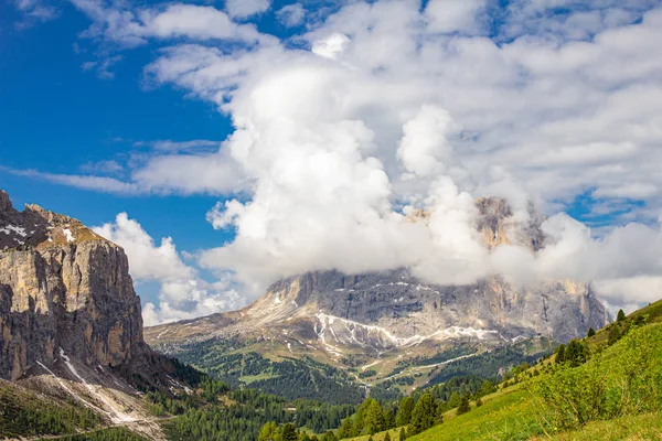 パッソ・セッラ・ディ・ヴァル・ガーデナ・ドロミテ、南チロル、アルト・アディジェ、イタリアから晴れた夏の日に雲の中のサッソルンゴ山へのカラフルなトップビュー。パスポルドイの上のドロミティアルプスのランコフェル — ストック写真