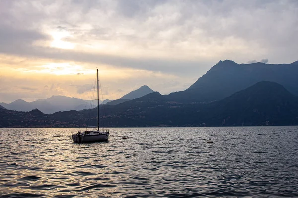 Como Gölü'ndeki Varenna köyünde limana demirlemiş yelkenliye Gece Manzarası. Arka plan alps dağlar ve su üzerinde manzara gün batımı. Lecco Milano Eyaleti. İtalyan Lombardiyası, İtalya, Avrupa