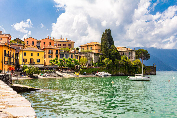Colorful view of the bay of Varenna ancient city with cozy restaurants, hotels and ships in the port connecting famous town with Menaggio and Bellagio. Shore of lake Como, Lombardy, Italy, Europe.