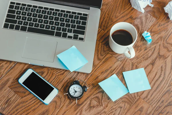 Ofis İşyeri dizüstü bilgisayar, saat, kahve fincanı ve ahşap masa üstünde smartphone ile