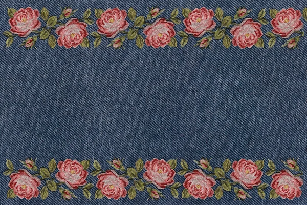 frame of embroidered pink roses on a blue denim background close up