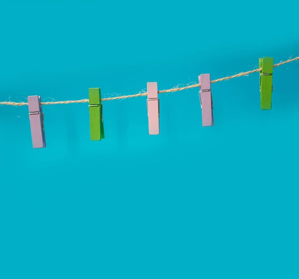 Multicolored wooden clothespins on a rope isolated on blue background photo