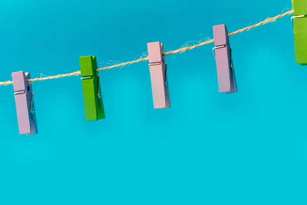 Multicolored wooden clothespins on a rope isolated on blue background photo