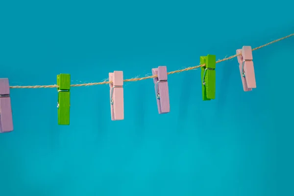 Multicolored wooden clothespins on a rope isolated on blue background photo