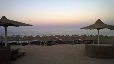 Mısır 'da günbatımının arka planında şemsiyeli plaj