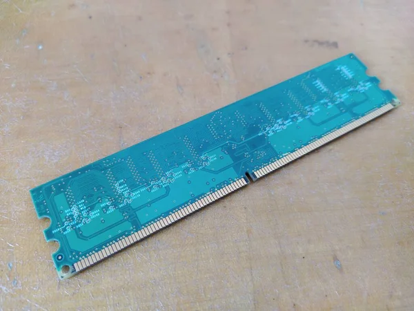 Single green computer RAM module on a wooden desk