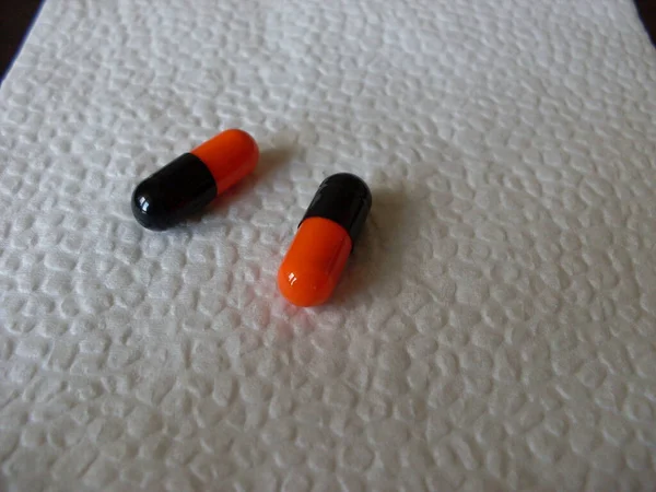 Schwarze Und Orangefarbene Pillen Auf Einer Weißen Serviette Großaufnahme — Stockfoto