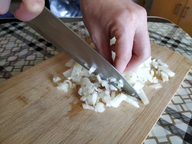 Tahta kesme tahtasıyla soğan doğrayan kadın.