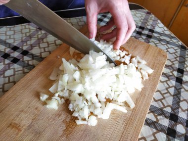 Tahta kesme tahtasıyla soğan doğrayan kadın.