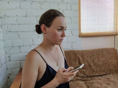 Kadın kanepede oturuyor, telefonu kullanıyor ve gelecekteki randevusunu düşünüyor, arkadaşlarıyla buluşuyor.