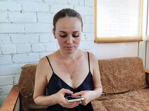 Genç bayan telefona bakıyor ve gülümsüyor.