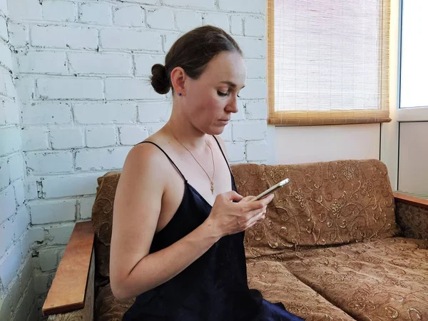 Kadın kanepede oturuyor, telefonu kullanıyor ve gelecekteki randevusunu düşünüyor, arkadaşlarıyla buluşuyor.