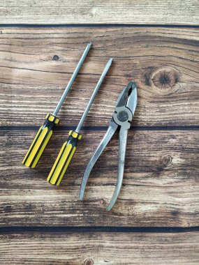 Tahta bir masada çelik pense ve tornavida.