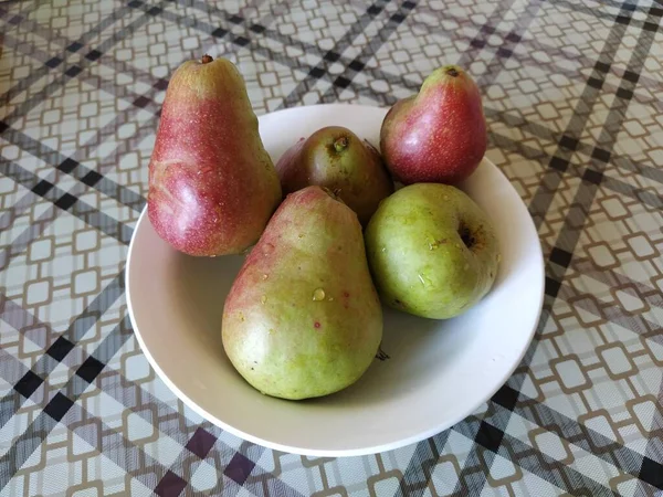 Plate with red-green pears on the table