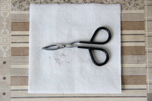 Tweezers and nose hair on the white napkin