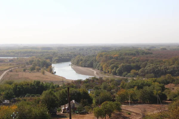 Hill below a valley with river and trees and a village below