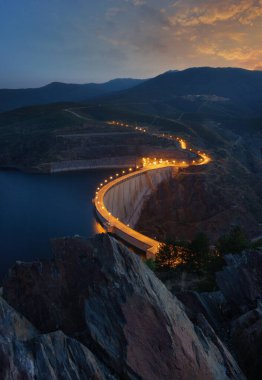 Presa de mumyalama iluminada al atardecer con grupo de rocas en primer plano