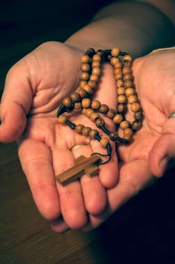 Manos caucsicas of reciendo rosario de cruz y cuentas de madera