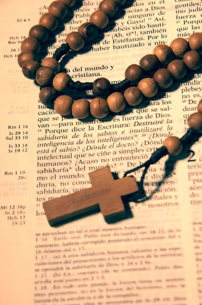 Rosario de Cruz y cuentas de madera sobre biblia abierta en pasaje en Castellano