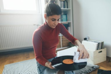 Hippi kızın elinde en sevdiği plak plağı var. Düşük açılı bir kız evde müzik dinlemekten hoşlanıyor.
