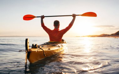 Aktif tatillerin tadını çıkar. Aktif kıdemli adamın arka görünüşü kano küreklerini yüksek tutuyor