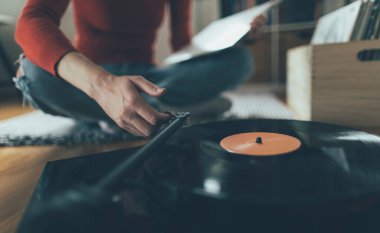 Vinil plak çalıyorum. Kadının yerde oturup pikapta müzik çalarkenki görüntüsü.