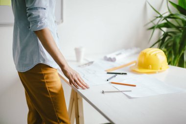 Kadın mimar bir plan çizer, tasarım, geometrik şekiller ofis masasındaki büyük kağıt üzerine kurşun kalemle çizer..