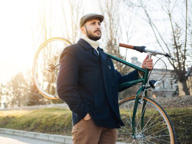 Bisikletli hippi eğleniyor. Sakallı adam parkta bisiklet sürmeyi sever.