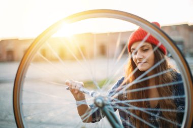 Dışarıda bisikletini tamir eden kırmızı şapkalı tatlı bir kız.