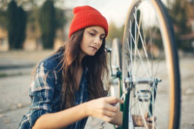 Dışarıda bisikletini tamir eden kırmızı şapkalı tatlı bir kız.