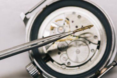 Saatçi kol saatini, mekanik saati tamir ediyor.