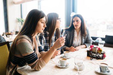 Kafede oturan ve kahve içen çekici kızlar.