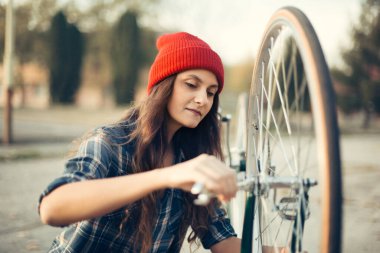 Dışarıda bisikletini tamir eden kırmızı şapkalı tatlı bir kız.