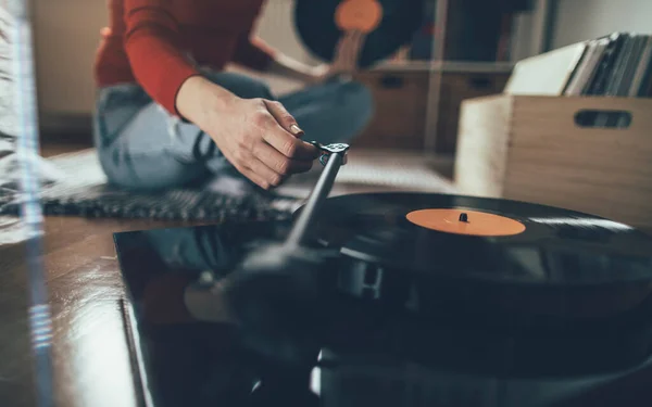 Vinil plak çalıyorum. Kadının yerde oturup pikapta müzik çalarkenki görüntüsü.