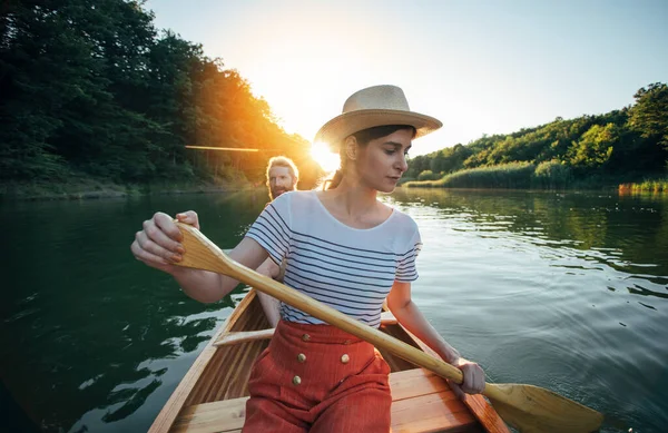 Young couple sailing on canoe on river sunset
