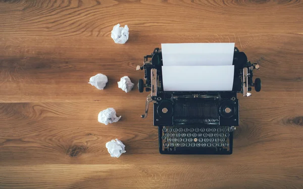Kırsal ahşap arka planda, etrafı buruşmuş kağıtlarla dolu bir daktilo. İlham sorunu kavramı
